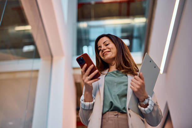istock Smiling businesswoman using smartphone in modern office building 2214939459