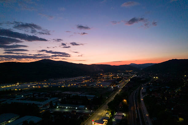 Aerial view of an industrial zone with illuminated streets and buildings during a vibrant sunset