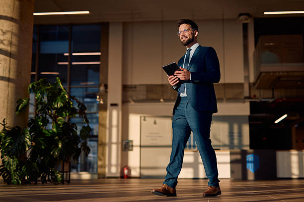 istock Businessman walking in modern office building using digital tablet 2214941345