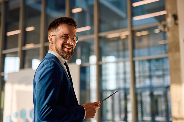 istock Smiling businessman holding tablet and looking at camera in modern office 2214941744