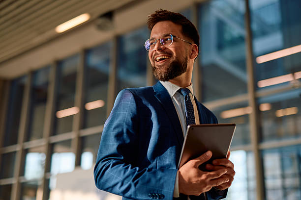 istock Smiling businessman holding tablet and looking away in modern office 2214941772