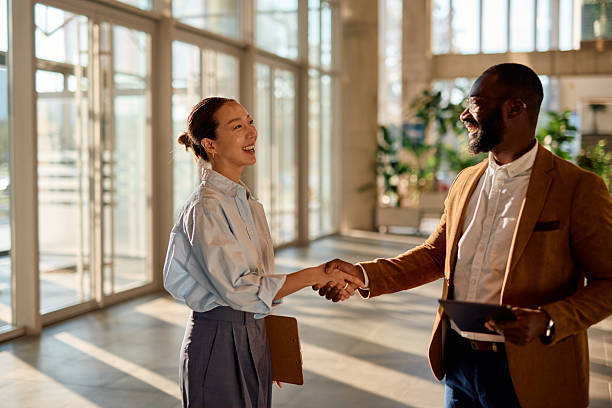 istock Two smiling businesspeople shaking hands in modern office 2214941797