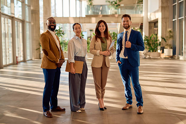 istock Four business people smiling standing in modern office building lobby 2214941995