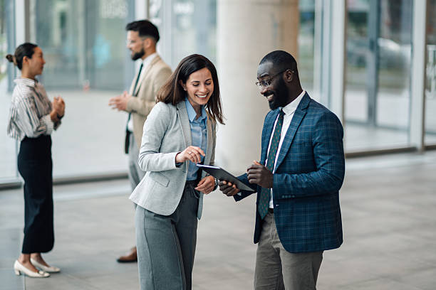 istock Business colleagues discussing work on digital tablet in office lobby 2214945713