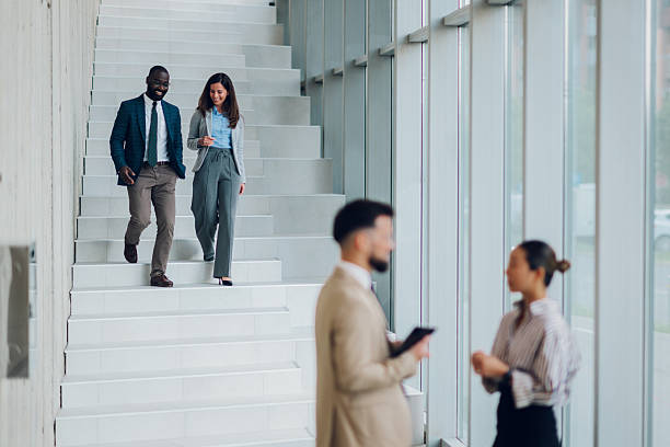 istock Businesspeople walking down stairs in modern office building 2214945725