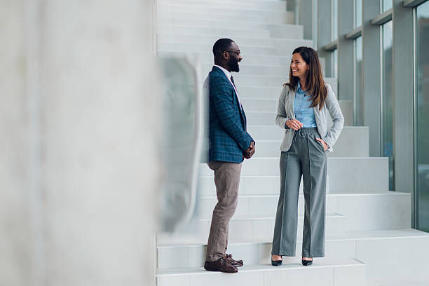 istock Businesspeople chatting on stairs in modern office building 2214945729