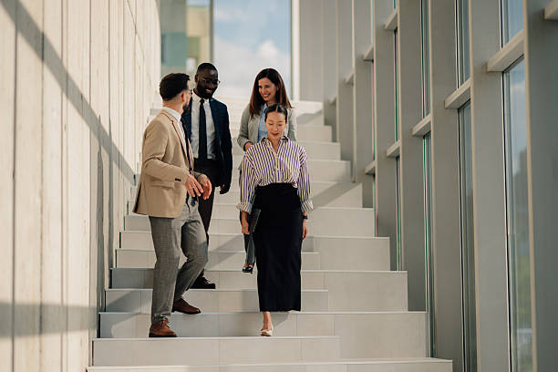 istock Business people walking down stairs in modern office building 2214945765