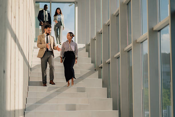 istock Businesspeople walking down stairs in modern office building 2214945767