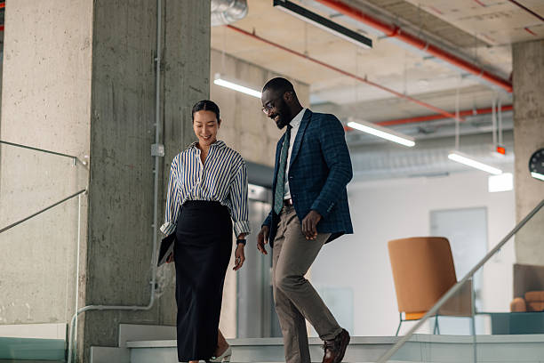 istock Businesspeople walking downstairs and talking in modern office 2214945895