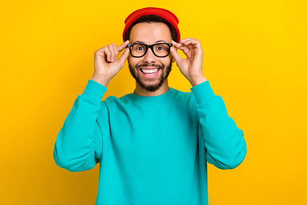 istock Portrait of satisfied friendly man with beard dressed turquoise pullover fingers touching glasses isolated on yellow color background 2214950313