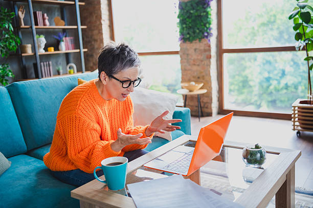 istock Photo of shocked impressed elderly lady wear orange pullover having working trouble modern device indoors apartment room 2214950562
