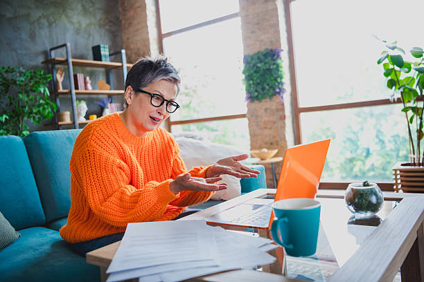 istock Photo of impressed amazed elderly lady wear orange pullover communicating modern device indoors apartment room 2214950621