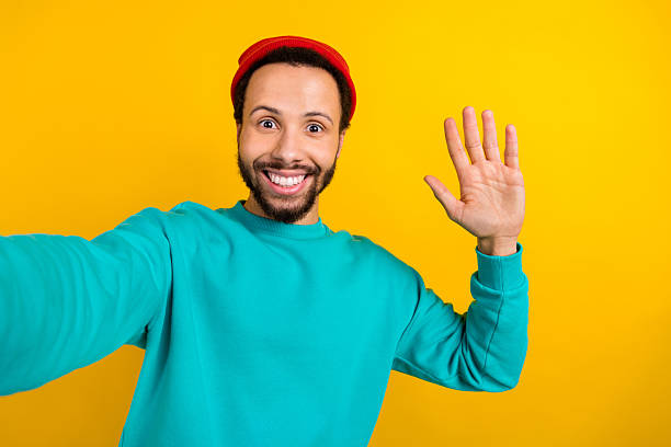 istock Portrait of optimistic nice man with beard dressed turquoise pullover make selfie waving palm say hi isolated on yellow color background 2214950899