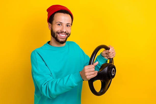 Portrait of satisfied man with beard dressed turquoise pullover hold steering wheel test new car isolated on yellow color background.
