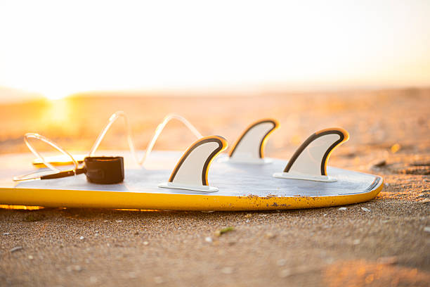 Yellow surfboard on a sunny beach in the golden hour. Adventure sports and beach holidays concept.