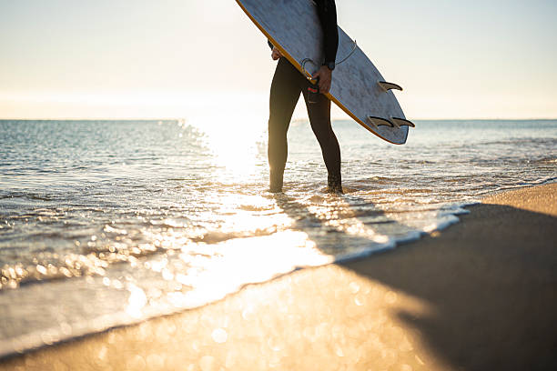 istock Beach Holiday. Surfer Entering Ocean At Golden Hour 2214951275