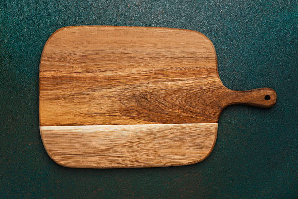 istock Wooden cutting board displayed on a textured green surface with natural grains 2214951679