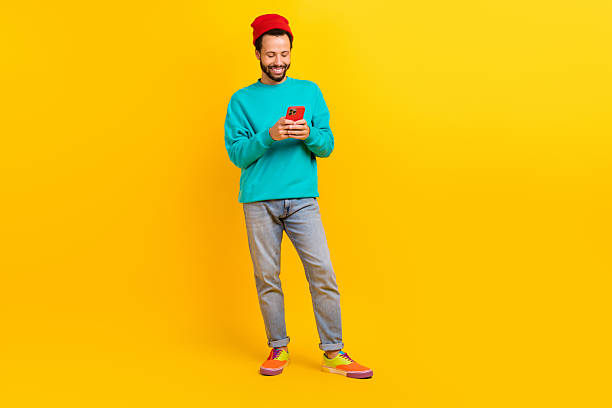 istock Full length photo of satisfied man dressed turquoise pullover look at smartphone read notification isolated on yellow color background 2214952225