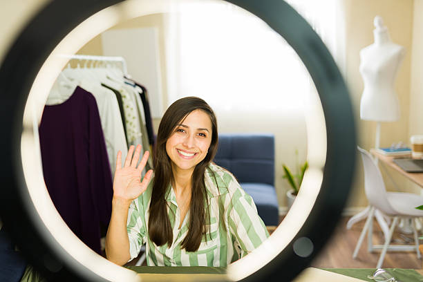 istock Clothing designer waving at camera during livestream from home studio 2214954068