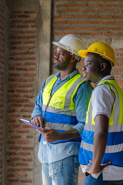 istock An African male engineer is overseeing the construction of a building with construction workers who are checking and planning the work on his tablet. 2214959067
