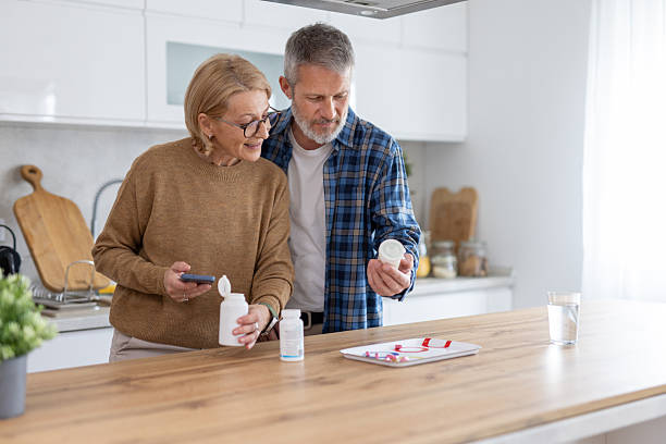 istock Couple Examining Medicine Labels in Modern Kitchen 2214959349