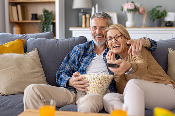 istock Smiling Couple Sharing Popcorn While Watching a Movie Together 2214959393