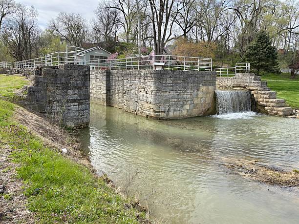 istock Historic stone canal lock with flowing waterfall in small town park 2214963632