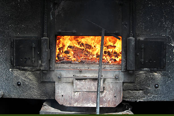 A wood-fired oven roars with flames, showcasing the heat and energy from burning logs inside. This traditional cooking method fills the surrounding area with warmth.
