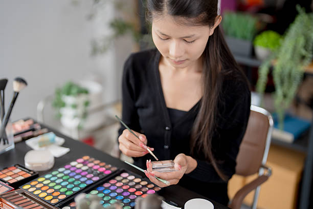 istock Asian woman applying make up foundation and concealer make up on face with cosmetics makeover Daily beauty routine at home. 2214983541