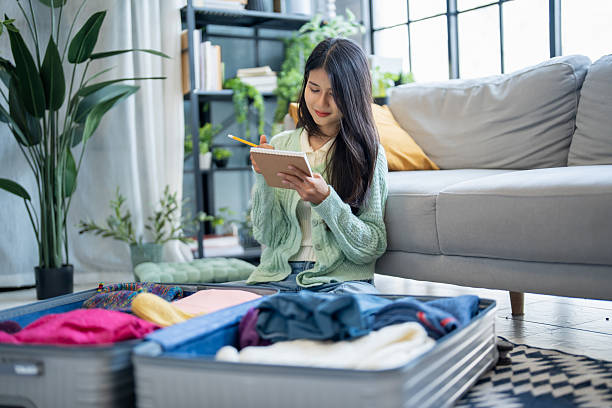 istock Happy asian Woman doing checklist for packing suitcase before holidays trip. 2214984846