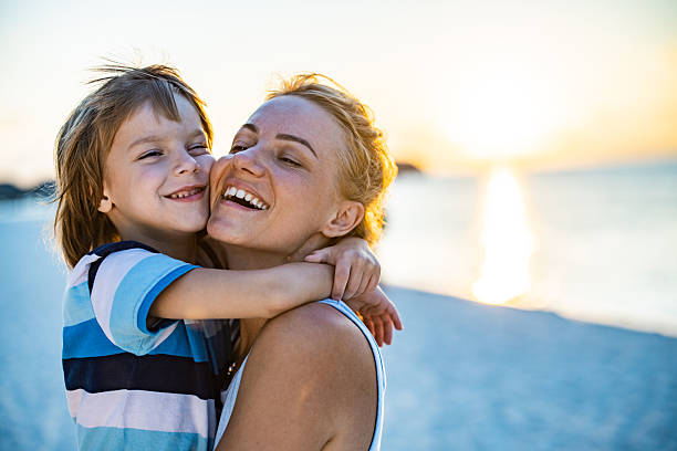 istock Loving single mother and son embracing on the beach at sunset. 2214988653