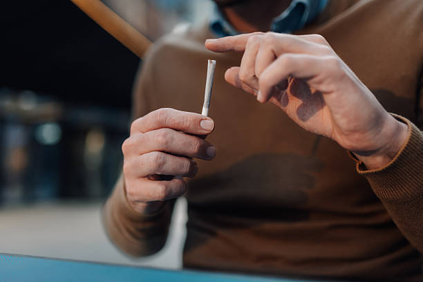 istock Man holding a hand-rolled cigarette, preparing to smoke 2214988872
