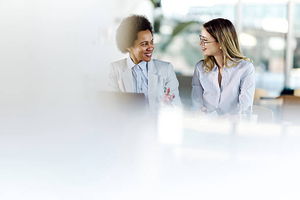 istock Female entrepreneurs talking while working on laptop at casual office. 2214989043