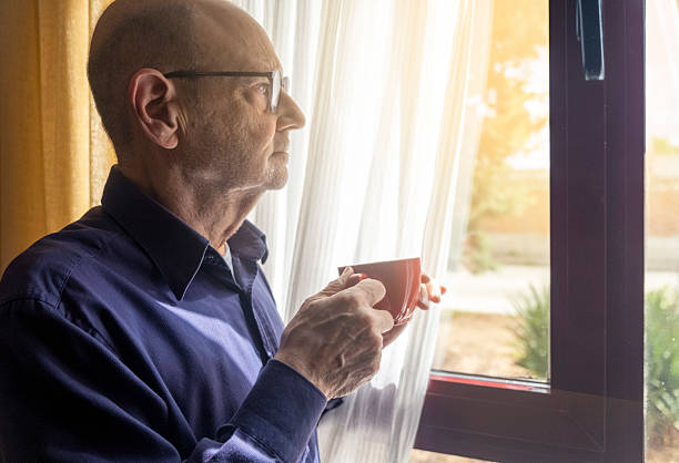 istock Elderly Man Relaxing by a Sunlit Window Holding a Hot Beverage 2214989365