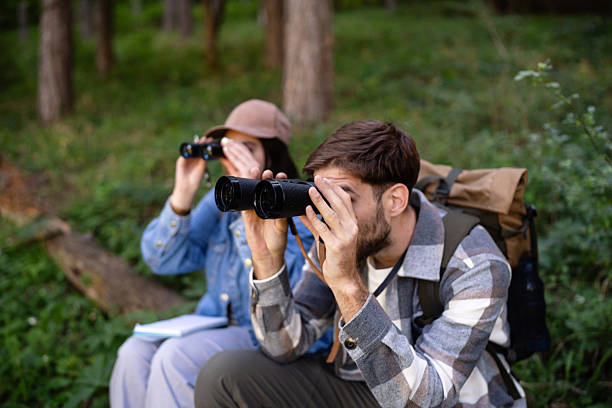 Young people birdwatching in a forested area with binoculars