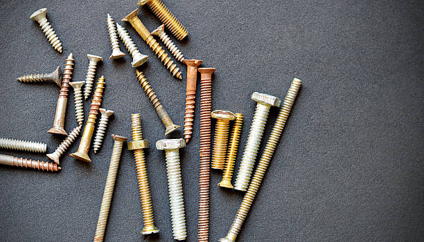 istock Table top view of heap or stack of several variety rusted rusty metal screws in different size  scattered over rough rustic dark black background like leather textured mat or slate or blackboard or road texture with copy space 2214991473
