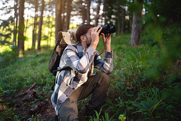 istock Man exploring nature with binoculars in a forested area during the day 2214992010