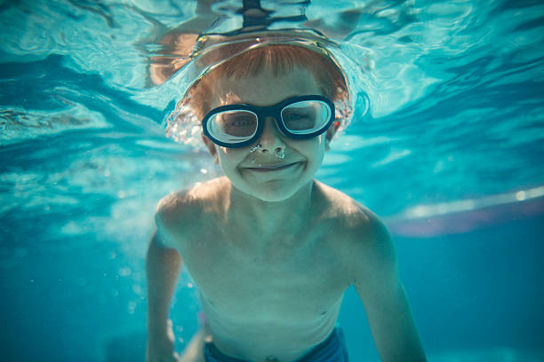 istock Underwater little boy swimmer captured mid-motion in a clear blue pool 2214992068