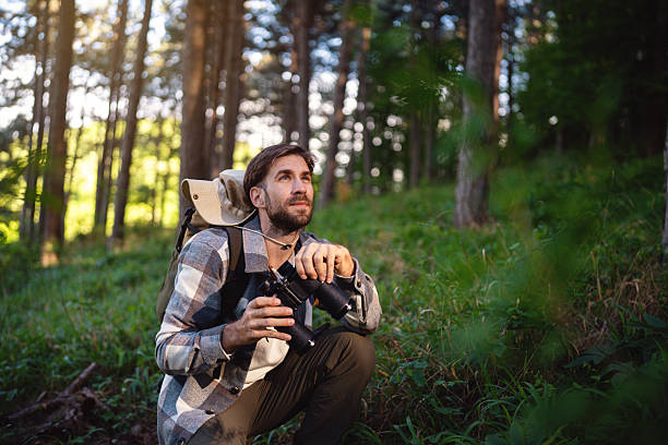 istock Man observing birds in a nature with binoculars in a serene forest setting 2214992107