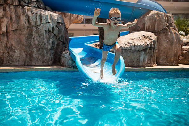 Boy happily watersliding on inflated waterslide in the backyard