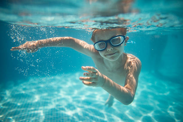 istock Underwater little boy swimmer captured mid-motion in a clear blue pool 2214992319