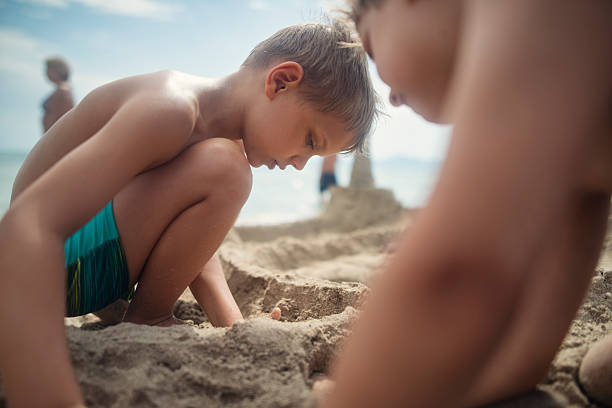 istock Two little boys building sandcastles on a sandy beach 2214992566