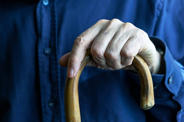 istock Elderly Person Holding a Wooden Walking Cane for Support 2214992661