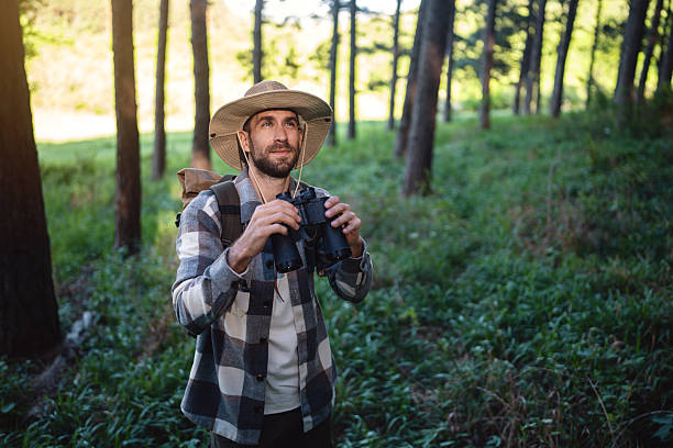istock Man birdwatching in scenic forest wearing hat and holding binoculars 2214994220