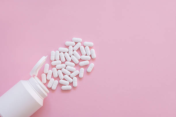 istock White tabletts or pills on the pink background with place for text. 2214997925