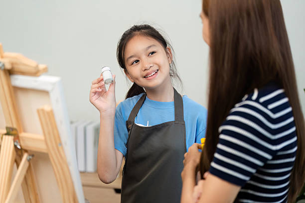 istock Creative Learning: Young Girl Showing Paint to Her Mentor 2214998733