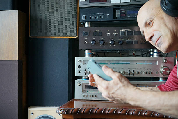 A man playing music from his smartphone to an old Hi-Fi system.