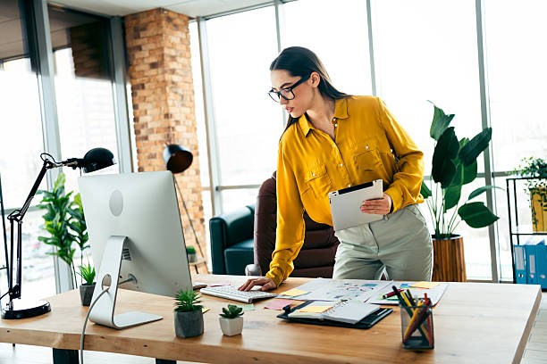 istock Young business professional in modern office workspace working on project with a thoughtful expression wearing a vibrant yellow shirt 2215000378