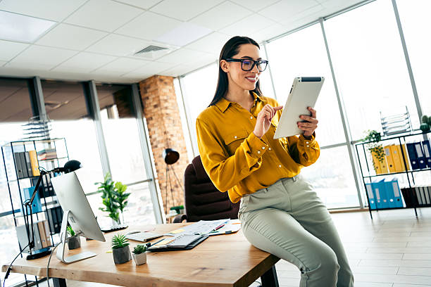 istock Confident businesswoman using a tablet in her modern office environment during the workday, dressed in casual attire and smiling. 2215000381