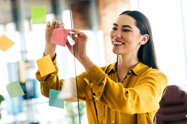 istock Confident businesswoman working in a bright modern office organizing tasks with sticky notes 2215000410